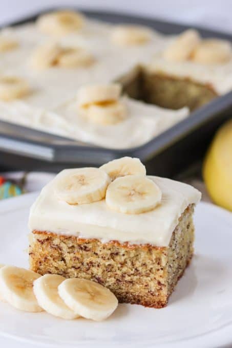 Banana Cake recipe topped with cream cheese frosting and bananas.