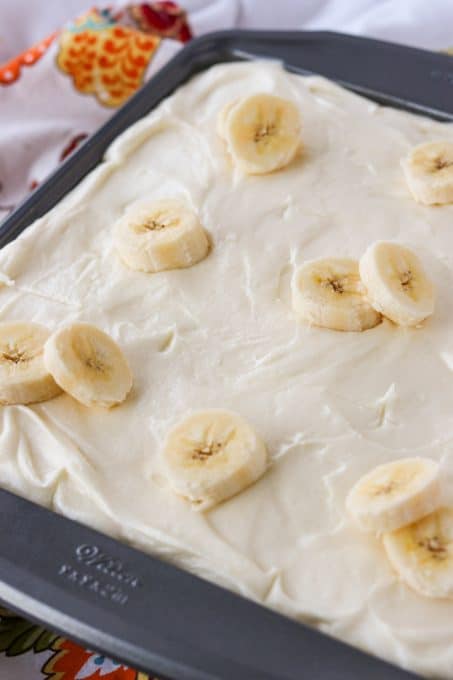 Banana cake topped with cream cheese frosting and bananas.