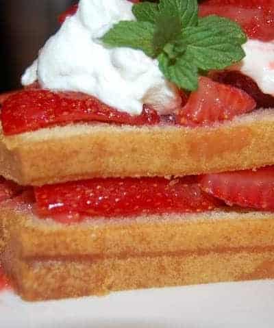 Layered Pound Cake topped with whipped cream and strawberries