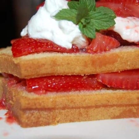 Layered Pound Cake topped with whipped cream and strawberries