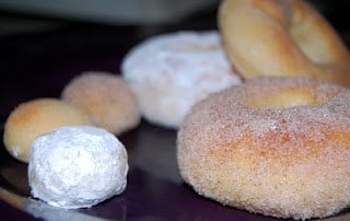 A variety of cinnamon, plain, and powdered doughnuts.