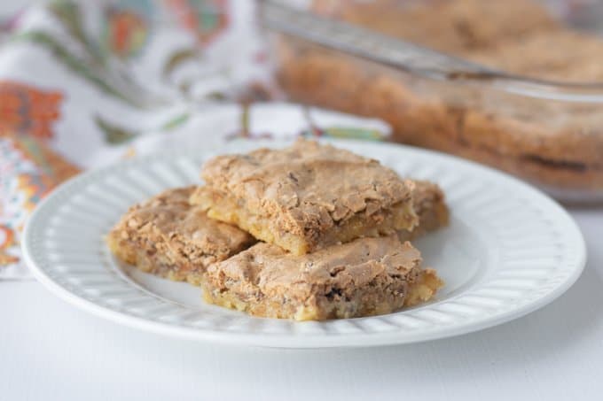 A plate of bars with a buttery crust, brown sugar and a nut meringue topping.