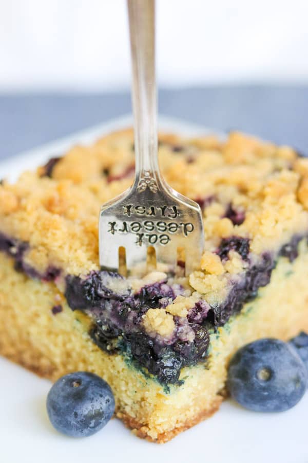 A fork sinking into a blueberry crumb cake.