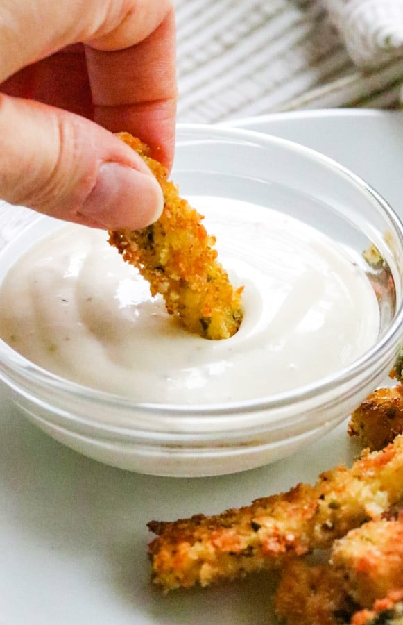 Zucchini stick being dipped in Ranch dressing.