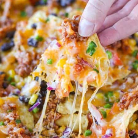Layers of chicken, cheese, and veggies on nachos.