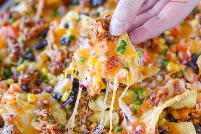 Layers of chicken, cheese, and veggies on nachos.