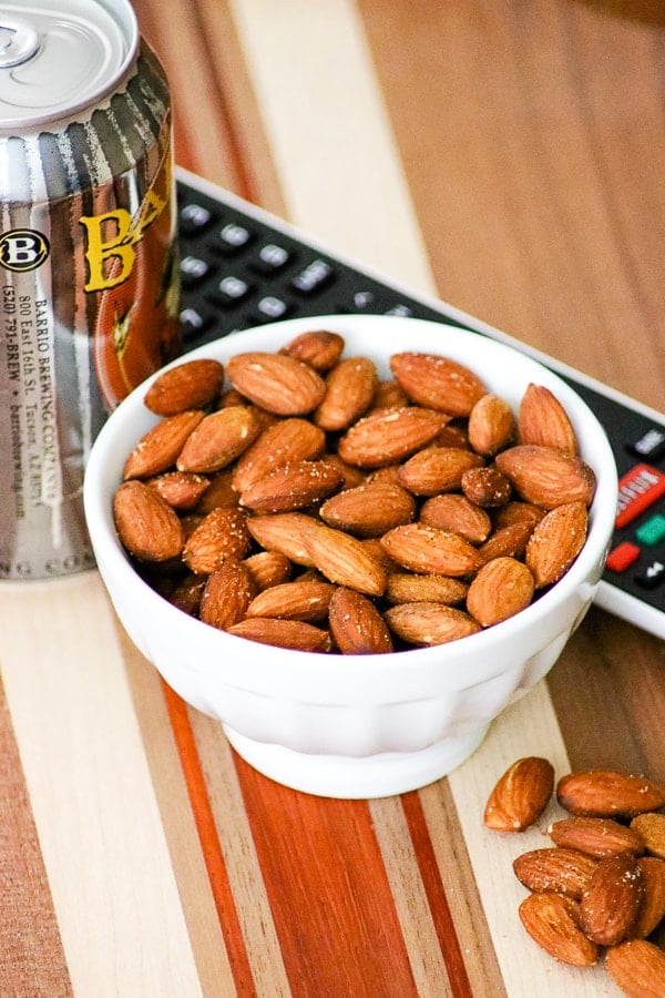 Bowl of Baked Spiced Almonds with a remote and can of beer.