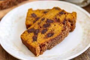 Two slices of Chocolate Chunk Pumpkin Bread with cinnamon sugar topping on a plate.
