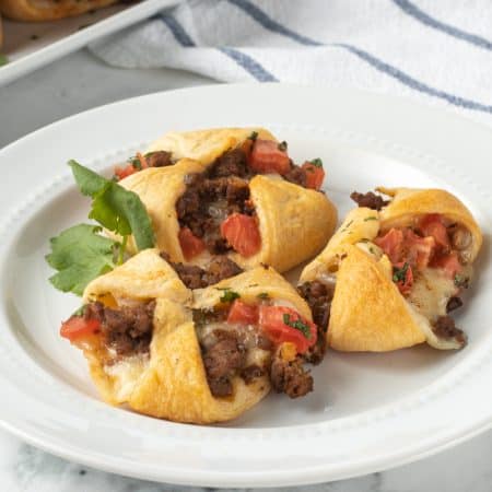 Taco seasoned meat with tomatoes and cheese in crescent dough.
