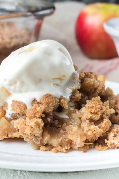 A scoop of vanilla ice cream on top of a crisp made with apples.