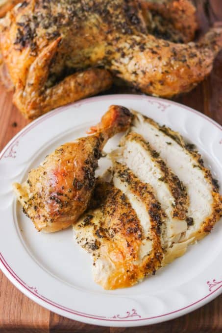 A drumstick and slices of chicken coated in herbs and lemon.