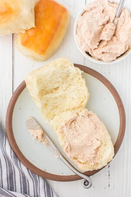 Cinnamon honey butter spread on a soft dinner roll.