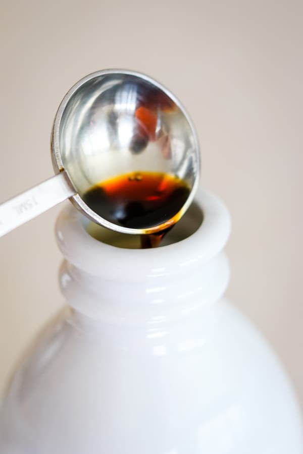 Pouring vanilla extract into the Homemade French Vanilla Coffee Creamer.