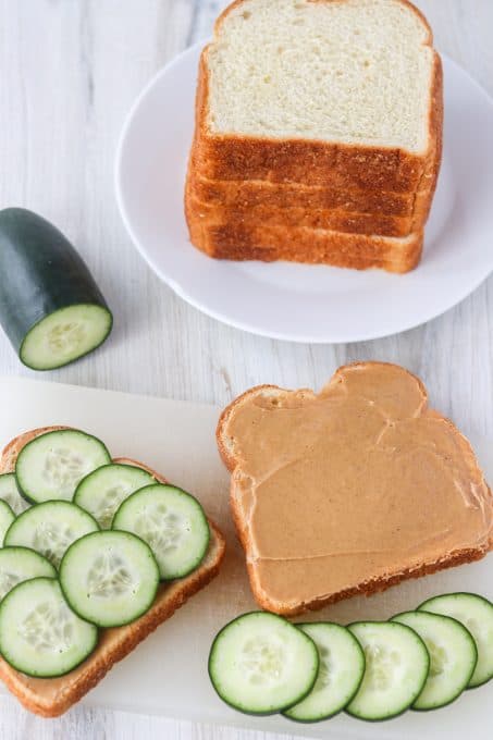 Putting together a sandwich with peanut butter and cucumber slices.