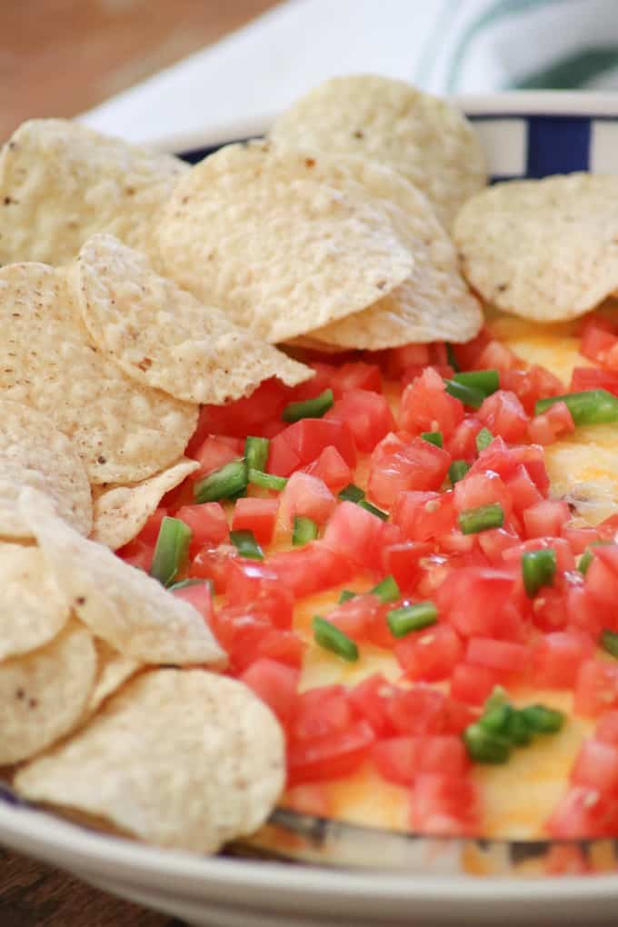 This Taco Dip is an easy game day dish to make, and fun to serve. The four layers of deliciousness are sure to please your hungry crowd. This dip of refried beans, taco seasoned ground beef, sour cream and Mexican cheese topped with diced tomato, jalapeño, and served with tortilla chips is a fan favorite at our house!