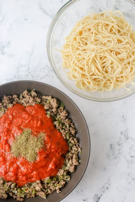 Cooked spaghetti and cooked ground beef and pasta sauce ready to be mixed together.