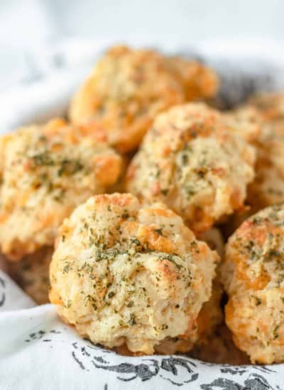 A basket full of biscuits with cheddar and Monterey Jack cheeses and garlic butter.