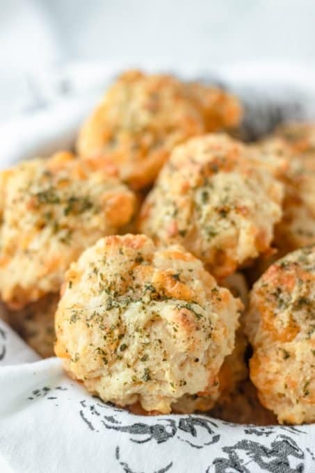 A basket full of biscuits with cheddar and Monterey Jack cheeses and garlic butter.