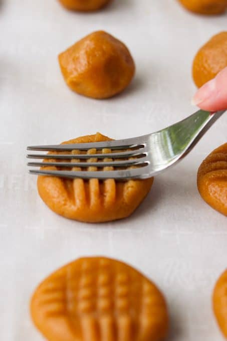 Flattening peanut butter cookies with a fork.