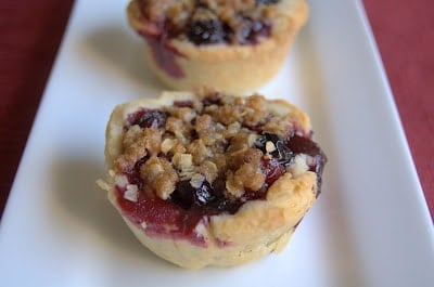 A bite-size pie filled with a fresh blueberry and cherry filling covered with a crumb topping.