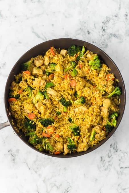 A skillet full of curried rice, chicken and vegetables.