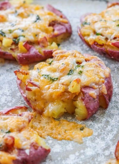 Potatoes topped with cheese and chives on a plate.