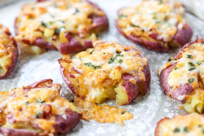 A side dish of small potatoes topped with cheese.
