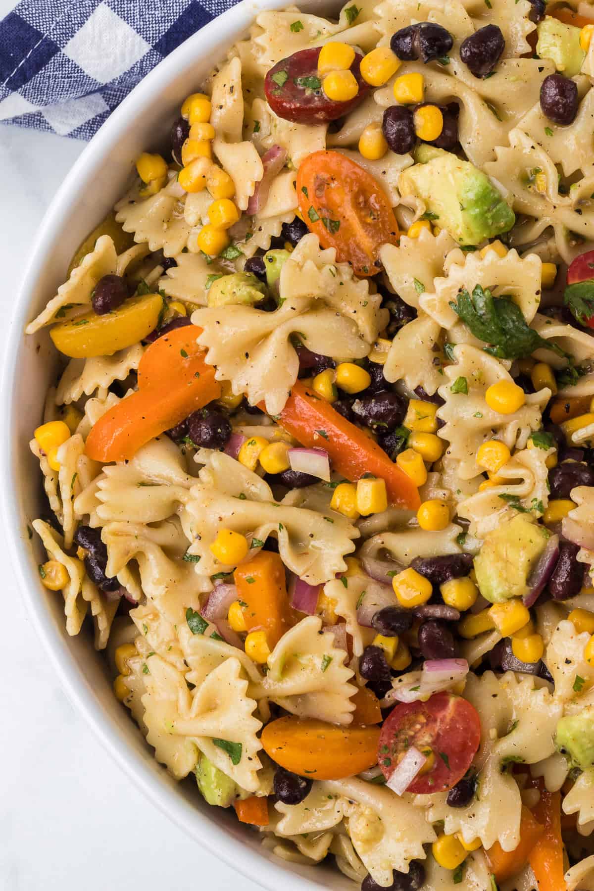 A cold salad with fresh veggies and black beans in a tangy dressing.