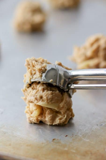 Dough for oatmeal cookies with peanut butter and apple placed on a cookie sheet.