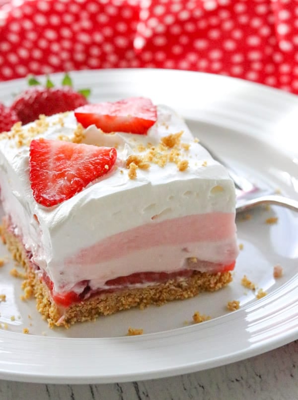 Strawberry Cheesecake Dream Bars - a graham cracker crust, fresh strawberries, a creamy strawberry cheese layer, strawberry creme pudding, topped with whipped topping. These are the perfect dessert to make when strawberries are in season! Strawberry Cheesecake Dream Bars.