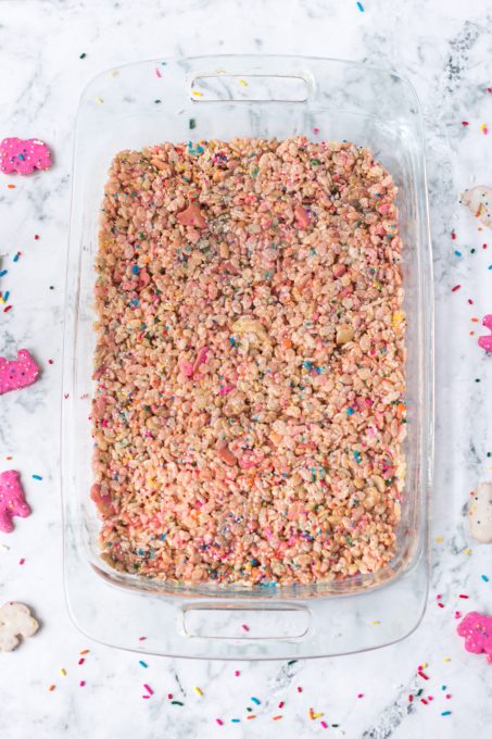A baking dish of crispy cereal treats with colorful cookies and sprinkles.