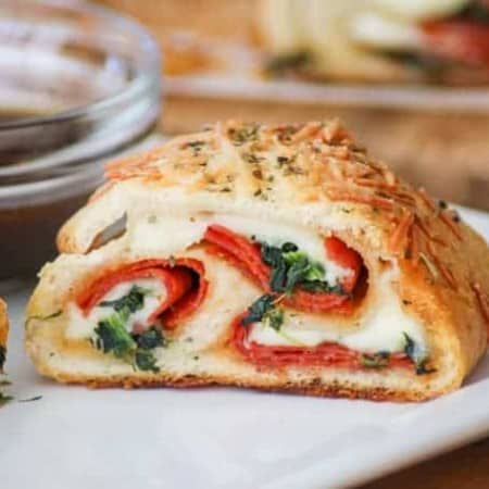 This Spinach Pepperoni Bread is pizza dough filled with spinach, pepperoni, and provolone. It makes a great weeknight dinner, is the perfect finger food for Game Day and is a recipe you'll be asked to bring again to that next potluck!