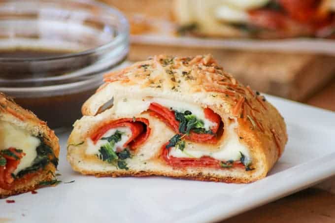 This Spinach Pepperoni Bread is pizza dough filled with spinach, pepperoni, and provolone. It makes a great weeknight dinner, is the perfect finger food for Game Day and is a recipe you'll be asked to bring again to that next potluck!