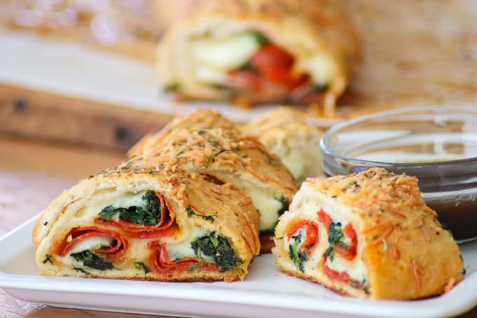 This Spinach Pepperoni Bread is pizza dough filled with spinach, pepperoni, and provolone. It makes a great weeknight dinner, is the perfect finger food for Game Day and is a recipe you'll be asked to bring again to that next potluck!