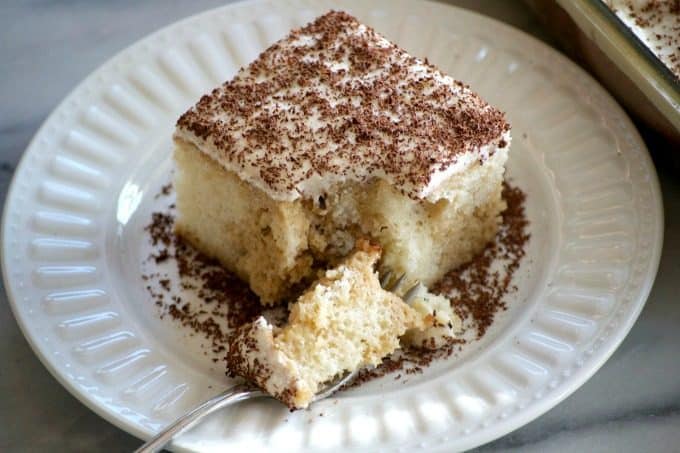 This Easy Tiramisu Poke Cake is a simple white cake drizzled with a sweetened coffee syrup, and topped with a whipped mascarpone vanilla frosting.