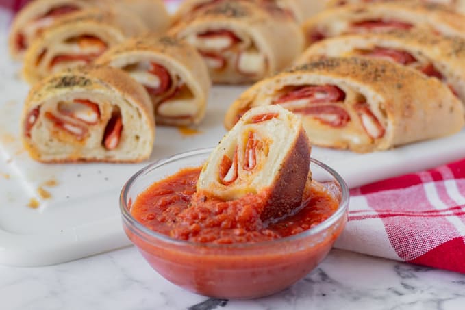 Dipping a bread stuffed with pepperoni and cheese in marinara.