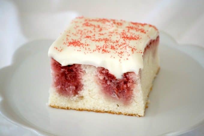 This Strawberry Poke Cake made from scratch with a white cake, strawberry sauce and cream cheese frosting is a perfect Valentine's Day or any day dessert.