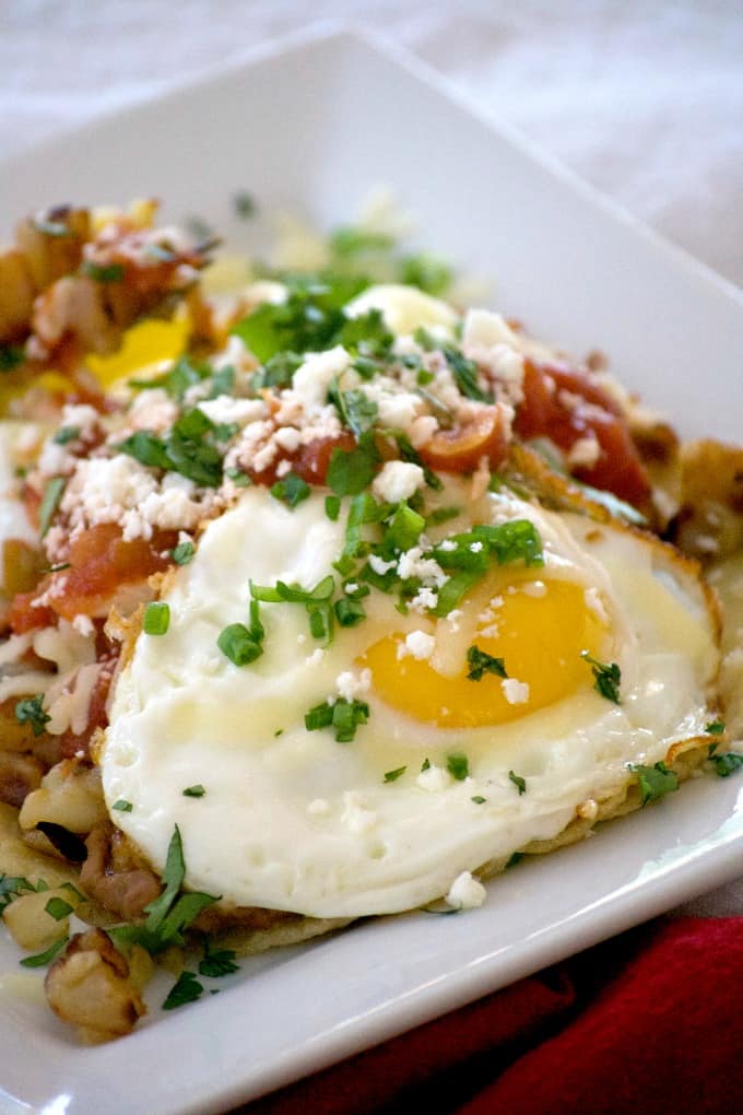 Loaded Huevos Rancheros are tortillas topped with refried beans, Potatoes O'Brien, salsa, eggs and cheese - a hearty breakfast that's full of great flavor!