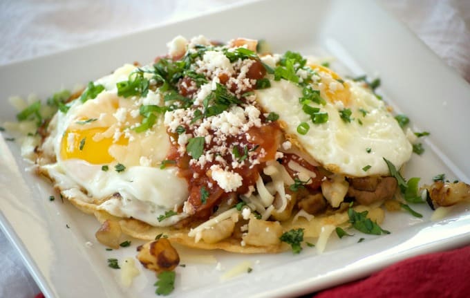 Loaded Huevos Rancheros are tortillas topped with refried beans, Potatoes O'Brien, salsa, eggs and cheese - a hearty breakfast that's full of great flavor!