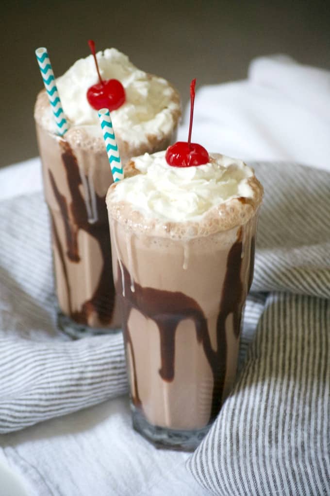 This Double Chocolate Malted Milkshake topped with whipped cream and a cherry is the perfect cold treat to satisfy a chocolate craving on a hot summer day.