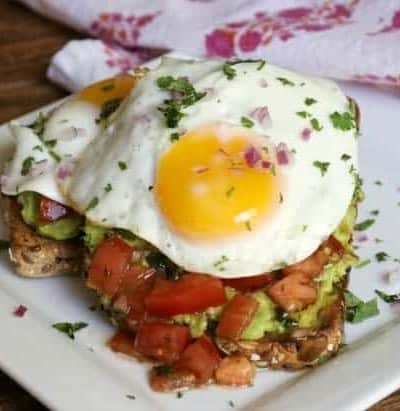 Bruschetta Fried Egg Avocado Toast with whole grain bread, smashed avocado, marinated tomato and a fried egg are sure to give you a great start to your day!