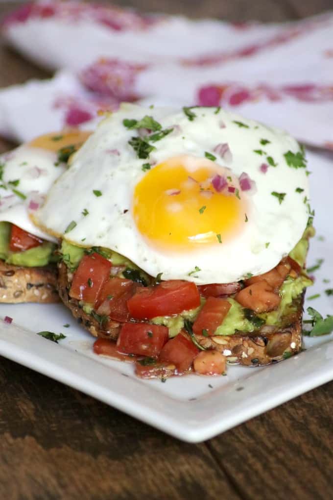 Bruschetta Fried Egg Avocado Toast with whole grain bread, smashed avocado, marinated tomato and a fried egg are sure to give you a great start to your day!