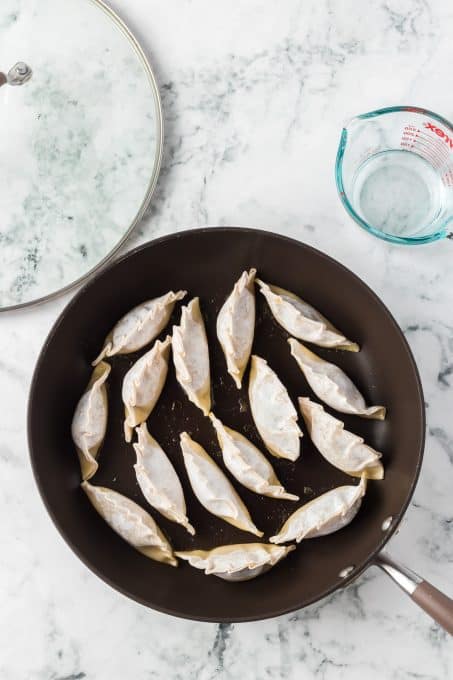 Frying the potstickers before steaming.