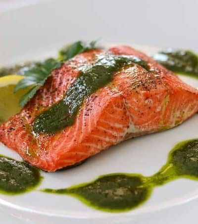 A salmon fillet topped with a chimichurri sauce.