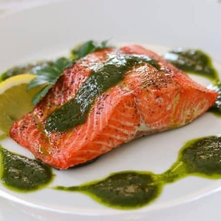 A salmon fillet topped with a chimichurri sauce.