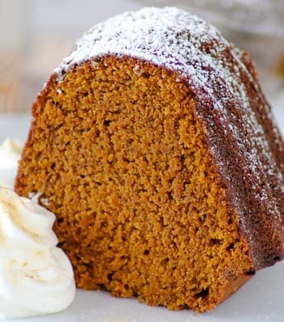 A slice of Chai Spiced Pumpkin Cake with dollops of fresh whipped cream.