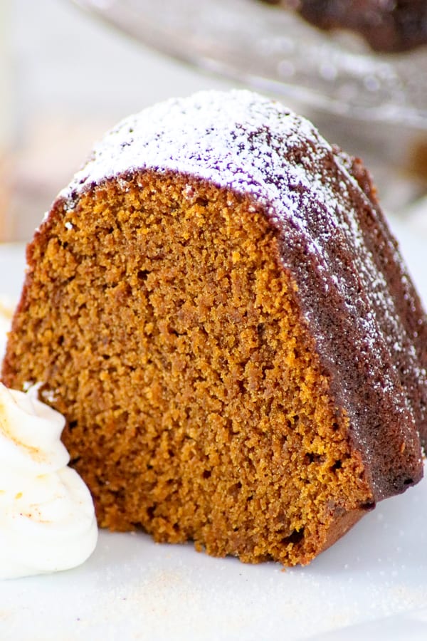 Chai Spiced Pumpkin Cake on a plate with swirls of fresh whipped cream.