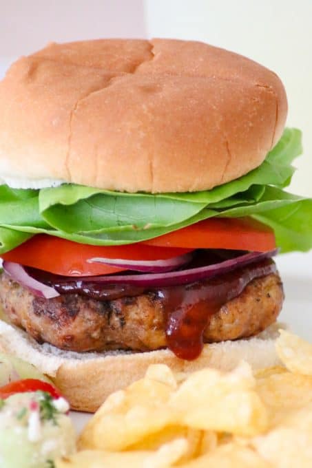 Lettuce, tomato, red onion, and BBQ sauce on top of a Cheesy Spiced Pork Burger.