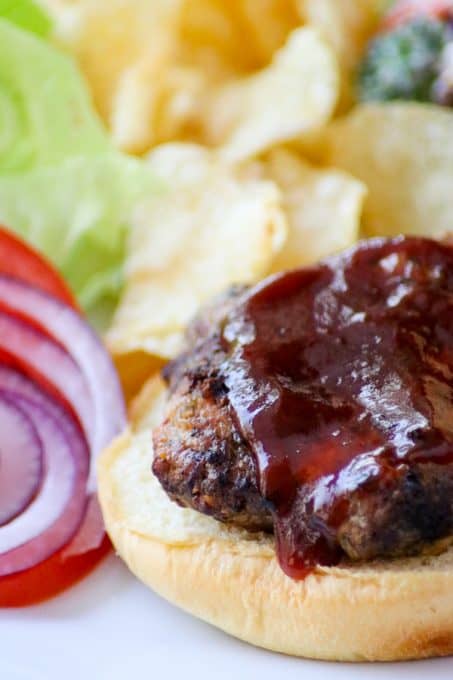 A Cheesy Spiced Pork Burger with BBQ sauce on top.