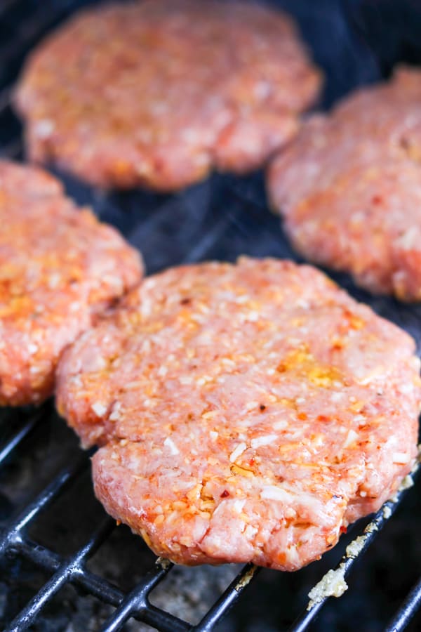Cheesy Spiced Pork Burgers cooking on the grill.